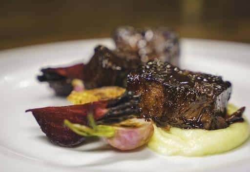 Bourguignon Short Ribs recipe served on a plate, by Bienvenue Restaurant